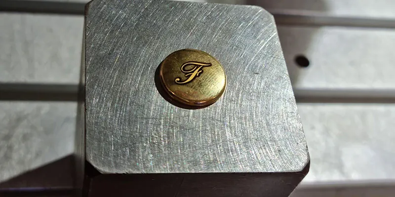 incisione laser di due copribottoni in oro